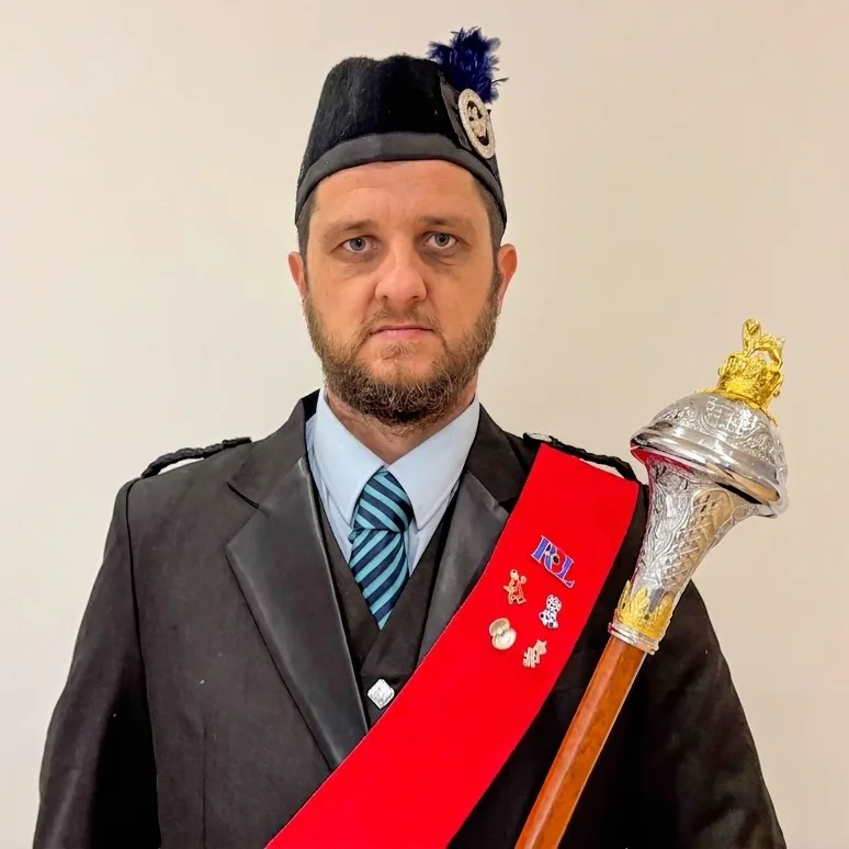 Gary Sansby in drum major uniform with red sash and mace